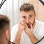 Man putting on his contact lenses in front of a mirror