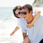 Happy young couple enjoying a solitary beach backriding