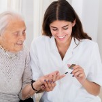 Doctor Checking Blood Sugar Level Of Senior Patient With Glucometer