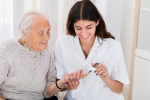 Doctor Checking Blood Sugar Level Of Senior Patient With Glucometer 