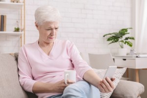 Woman squinting and holding phone far from eyes